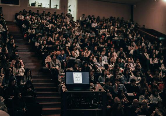 Dark lecture hall full of students watching a presentation